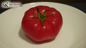 皿にのったトマトを中央に配置した写真。左上にShin Kitchenのロゴ。